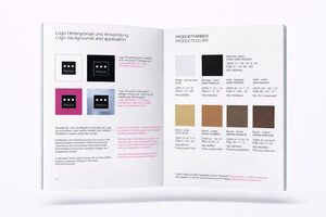 Eine aufgeschlagene Broschüre zeigt Richtlinien für Logohintergründe und Produktfarben, mit Logobeispielen auf schwarzem, weißem und magentafarbenem Hintergrund auf der linken Seite und Farbfeldern mit Beschreibungen auf der rechten Seite.
